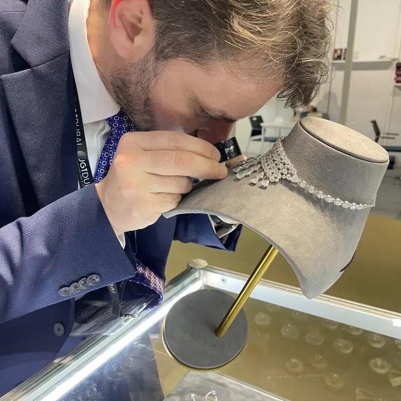 Esame gemmologico di una collana di diamanti con la lente