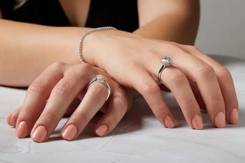 Due mani con anelli di fidanzamento e bracciale di diamanti