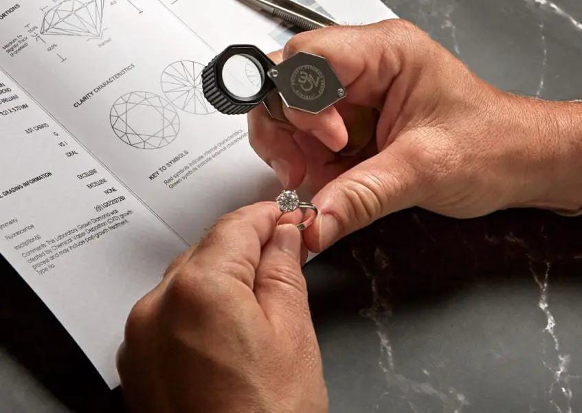 Un gemmologo esamina un anello con la lente